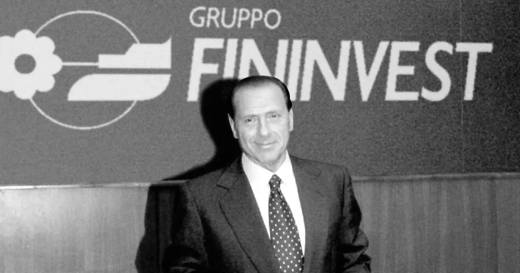 Silvio Berlusconi davanti al logo Fininvest negli anni Ottanta