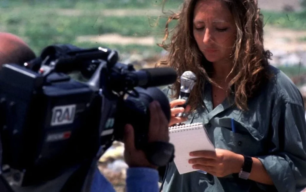 Ilaria Alpi durante un reportage in Somalia con microfono e taccuino davanti a una telecamera RAI